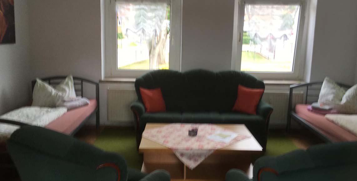 Wohnbereich der Pension Riel mit Sitzecke und Betten